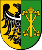 Herb powiatu średzkiego: po lewej stronie złote pole z czarnym orłem o białych detalach, po prawej zielone pole ze złotym godłem — dwa skrzyżowane berła zakończone koniczynkami i snop zboża pośrodku.