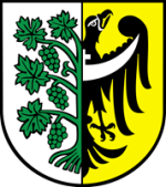 Herb Środy Śląskiej: po lewej stronie białe pole z zieloną winoroślą — liśćmi i gronami, po prawej złote pole z czarnym orłem z białym półksiężycem na piersi.