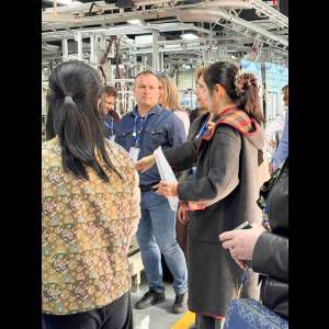 A group of people is gathered in a factory, discussing and observing the production process.