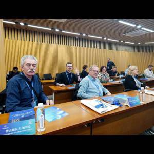 A group of people seated at a conference table, engaged in discussion and surrounded by notebooks and materials.