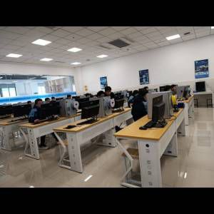 A classroom with multiple students working on computers at individual desks in a bright, modern space.