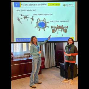 Two women present on agricultural drones, showcasing various models and their specifications in a conference setting.
