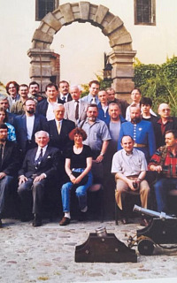 Dziedziniec Arsenału Wrocławskiego, 29 maja 1999 roku. Na zdjęciu widoczny jest profesor Zdzisław Żygulski, prezes Stowarzyszenia Miłośników Dawnej Broni i Barwy. Po jego prawej stronie siedzi Jerzy Zarawski, po lewej Lena Zajączkowska. W tle, w niemieckich mundurach, Wrocławscy Bracia Kurkowi. Po lewej stronie, z bronią drzewcową — tzw. partyzaną — stoi Wojciech Kopacz, obok grupa koleżanek i kolegów ze Stowarzyszenia. Fotografia została zamieszczona w pierwszym wydaniu Encyklopedii Wrocławia.
