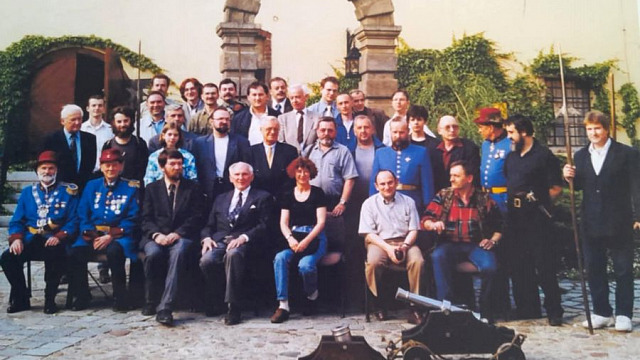 Dziedziniec Arsenału Wrocławskiego, 29 maja 1999 roku. Na zdjęciu widoczny jest profesor Zdzisław Żygulski, prezes Stowarzyszenia Miłośników Dawnej Broni i Barwy. Po jego prawej stronie siedzi Jerzy Zarawski, po lewej Lena Zajączkowska. W tle, w niebieskich mundurach, Wrocławscy Bracia Kurkowi. Po lewej stronie, z bronią drzewcową — tzw. partyzaną — stoi Wojciech Kopacz, obok grupa koleżanek i kolegów ze Stowarzyszenia. Fotografia została zamieszczona w pierwszym wydaniu Encyklopedii Wrocławia.