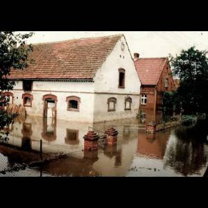 A house is partially submerged in floodwaters, with nearby structures and a flooded yard visible. Zakrzów/ Fot. arch. Sołectwo Zakrzów