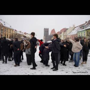 A snowy square is filled with a group of people in formal attire, gathered and interacting energetically.