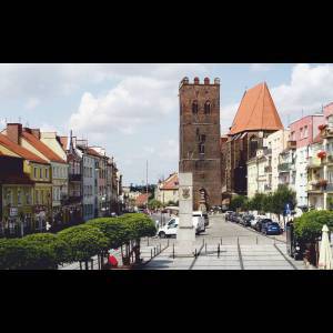 A serene town square with colorful buildings and a historic tower under a cloudy sky.