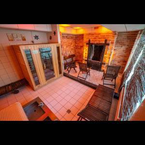 A cozy sauna room with wooden benches, a heated stone wall, and warm lighting for relaxation.