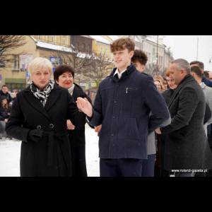 A snowy gathering with a young man smiling, flanked by two women, in a vibrant outdoor setting.