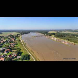 Aerial view of a river, surrounded by fields and a residential area, with construction near the water's edge.