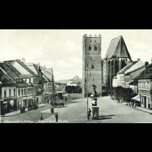 A historic street scene featuring old buildings and a prominent church tower, captured in black and white.