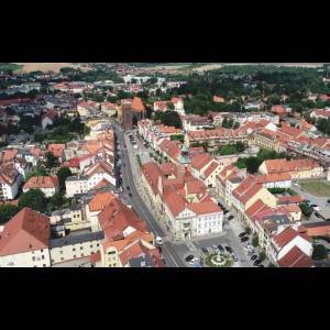 Aerial view of a picturesque town with red-roofed buildings, greenery, and winding streets.