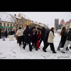 A group of people plays in the snow, creating a lively scene in a snowy town square.