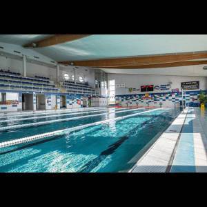 A spacious indoor swimming pool with lanes, seating, and bright lighting, ideal for swimming activities.