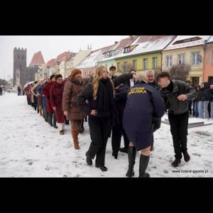 A line of people in snowy weather, some interacting with an authority figure in a blue uniform.