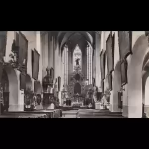 A historic church interior featuring tall arches, stained glass, and an ornate altar.