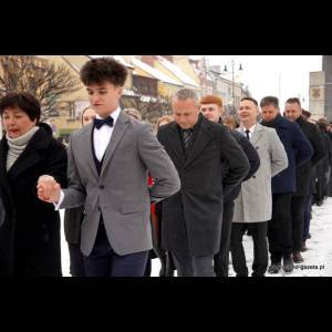 A group of elegantly dressed people walking in a line through snowy streets, celebrating a special event.